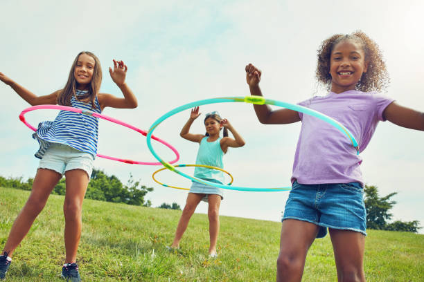 Shot of a group of young girls playing with hula hoops in the park