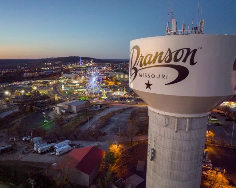 Water tower that says Branson Mo, with the city in the background